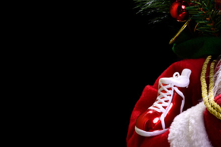 Photograph of a red Christmas shoe on a Santa Claus arm.The photo is illuminated with artificial...