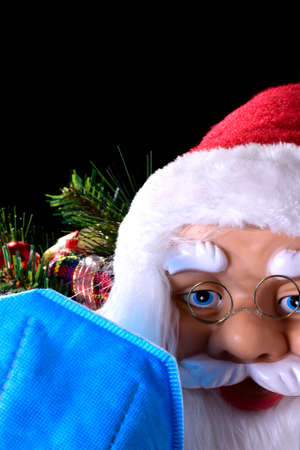 Photograph of Santa Claus with Christmas decorations in the background and an out-of-focus blue mask in the foreground.の写真素材