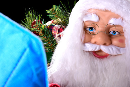 Photograph of Santa Claus with Christmas decorations in the background and an out-of-focus blue mask in the foreground.の写真素材