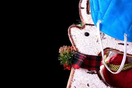 Photograph of a close-up of a Christmas ornament with a typical red bow and a blue hanging mask.The...