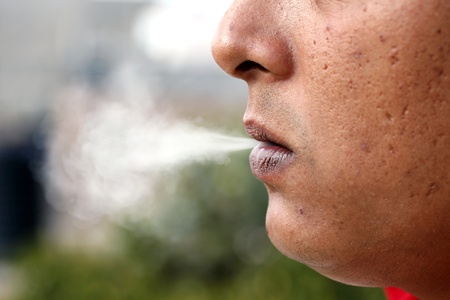 A young caucasian man exhaling cigarette smoke の写真素材