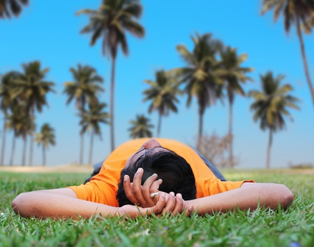 Young person relaxing in a garden on a lawn with coconut trees in the backgroundの写真素材