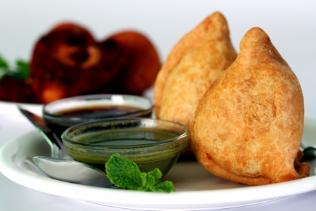 Popular indian, asian and african deep fried snack called samosa with spicy chutney and mintの写真素材