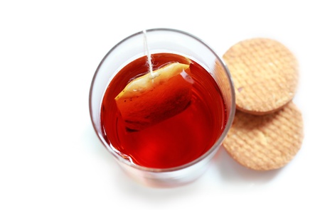 Closeup photo from the top of fresh tea in a glass made of tea powder from tea-bag dipped in water along with cookiesの写真素材