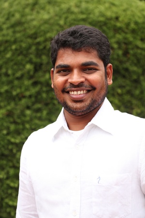 Closeup picture of attractive, handsome & smart asian/indian executive with smiling expression. The person is wearing a white shirt & the photo is shot in natural(garden) environmentの写真素材
