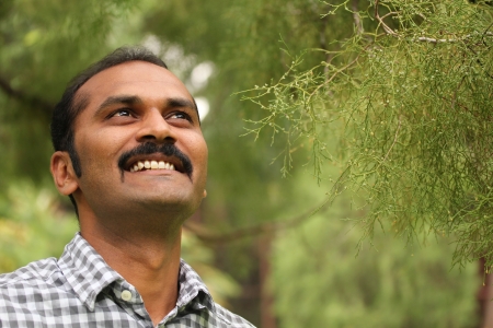 a hopeful, relaxed & happy asian/indian man looking confidently ahead. The executive is wearing a formal shirt &amp, the picture is shot in natural settingsの写真素材