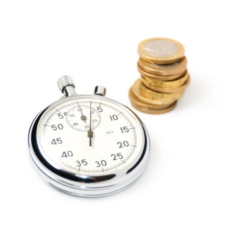 Stopwatch and a stack of coins, focus on the chronometerの写真素材