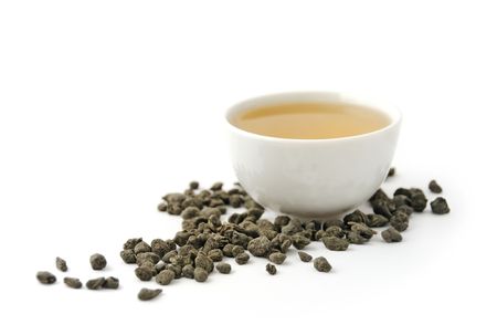 Chinese green tea in the ceramic bowl and tea leaves on white backgroundの写真素材