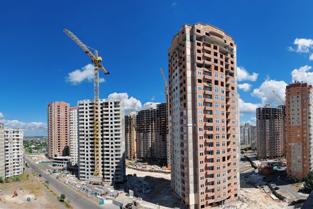 Panorama of a building site with a lot of residential highrises under construction against beautiful summer sky. の写真素材