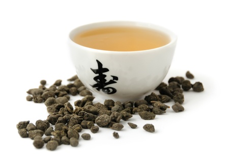 Hot green tea in the ceramic bowl and tea leaves on white backgroundの写真素材