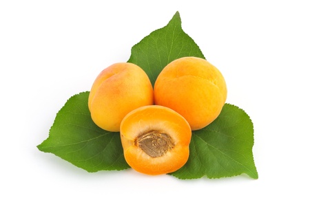 Three fresh juicy apricots with green leaves isolated on whiteの写真素材