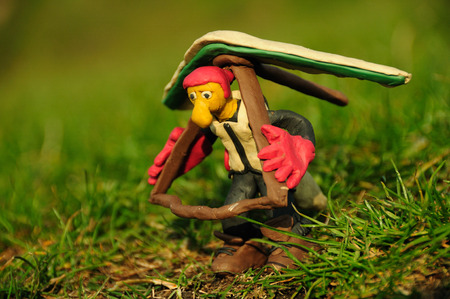Funny plasticine hangglider pilot figure holding his wing ready to take-off on a green grass taken with macro-lensの写真素材