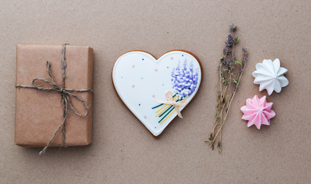 Valentines day gift in craft paper, flowers and heart shaped biscuit. Holiday conceptの写真素材