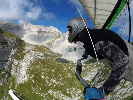 Brave extreme hang glider pilot soars in the thermal updrafts above  mountain rocks. Shot taken with...