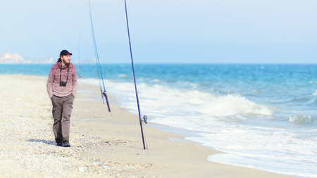 Peaceful man with a camera walks along the sea coast on a sunny dayの写真素材