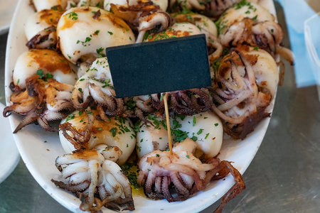 Grilled octopus with a blank price tag on a plate. Popular street sea food.の写真素材