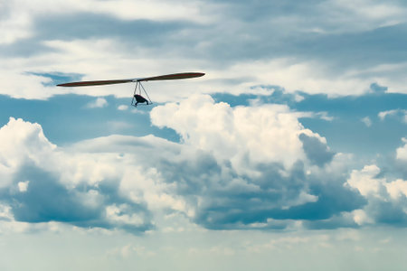Hang glider wing silhouette and beautiful sky with clouds. Extreme airborne sport