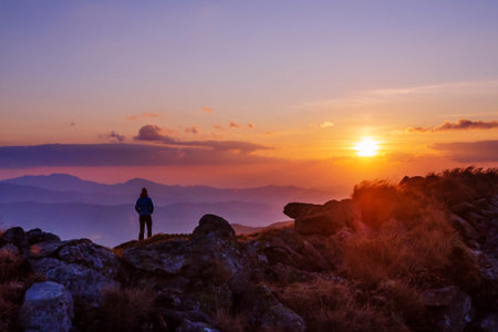 Lone tourist enjoying an amazing sunset in the mountains