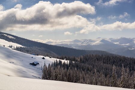 Highlands in winter, a Christmas landscape with wooden huts on the background of high mountainsの写真素材
