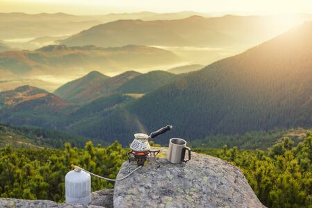 Hot morning coffee high in the mountains. Preparing coffee with gas camping stove. Morning outdoorsの写真素材