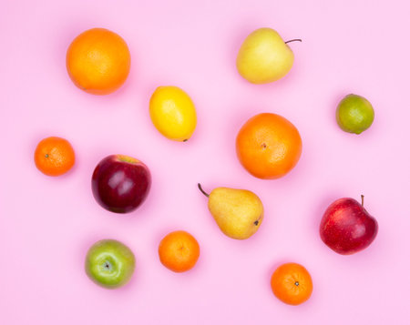 Variety of fruits on pink background, top view, flat layer