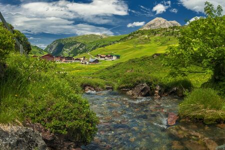 Alpine village in Austria. Tranquil landscape with mountain river, green pastures and mountains. Perfect place for rest, rehab and meditationの写真素材