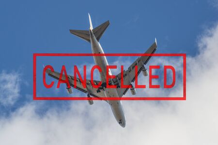 Passenger jet airplane in the sky and a stamp cancelled written by red letters. Coronavirus outbreak.の写真素材