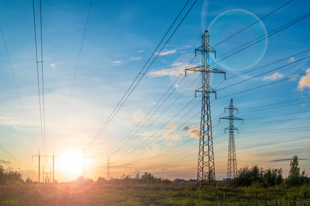 Multiple power lines at the sunset with sun flare. Energy distribution and environment