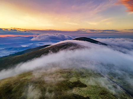 Amazing sunset in the mountains. Clouds flow over mountain ridge.