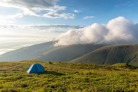 tent in the mountains, amazing morning with fog and cloudsの写真素材