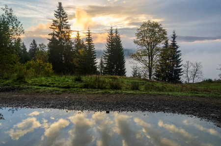 Cloud reflection in the puddles on the mountain road. Autumn weather