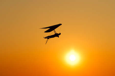 Hang glider wing silhouette against bright sunset sun. Dream of flying like a birdの写真素材