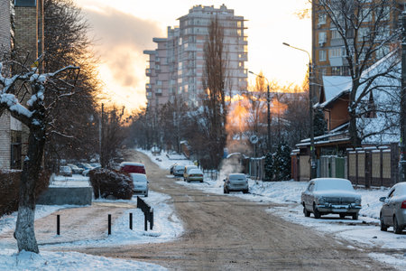 Cold winter evening in the city. Cars and road covered by mud and snow. Bad weather forcast.