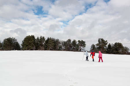 Hiking walking through a snowy field in winterの写真素材