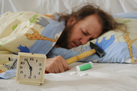 Sleeping man with a hangover. Funny sleeping man with hammer and headache pills and alarm clock in...