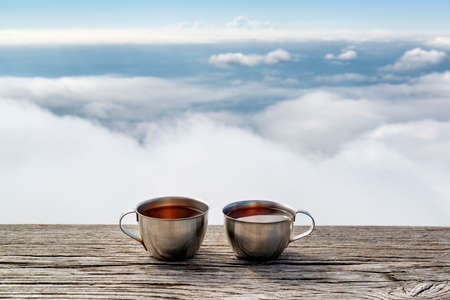 Two cups of herbal tea in an alpine rest place with amazing view on clouds belowの写真素材