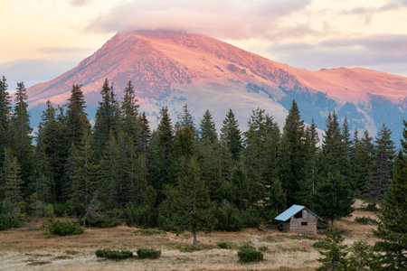 Wooden tourist hut with beautiful mountain illuminated by evening sun on the background