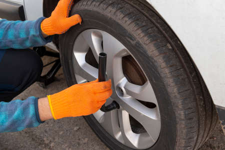 Flat tire replacing. Driver hands with wheel wrench near the car wheel.の写真素材