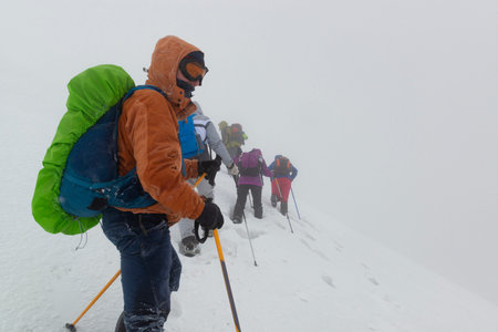 Group of hikers trying to survive in the deep snow in winter mountains during bad weather and heavy...