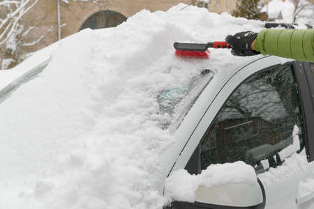 A car owner removing snow of his car in winterの写真素材