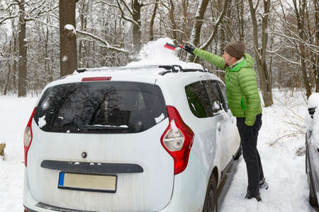 Man cleaning car from snow for a winter driveの写真素材