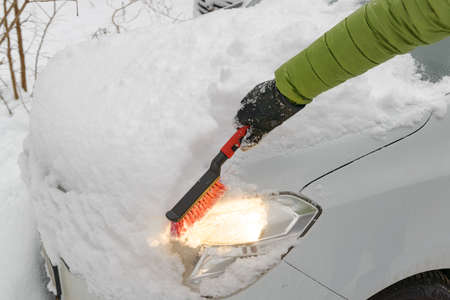 Man cleaning his car from the deep snow after bad weather with heavy snowfallの写真素材