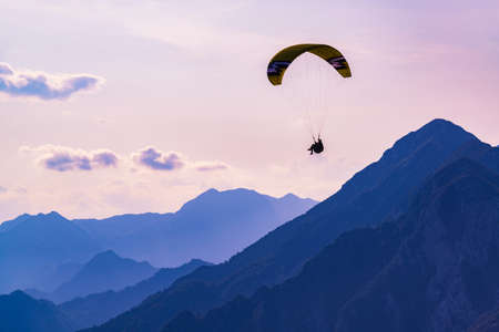 Dream flight in the mountains. Paraglider in the sunset sky of Bordano, Italyの写真素材