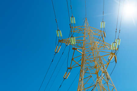 High voltage power line pylon shot from below with sun flare. Concept for energy, electricity, industry, power transmissionの写真素材
