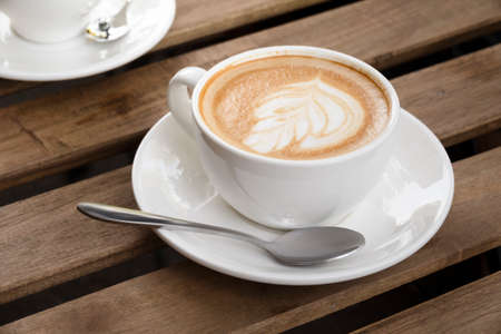 Morning cappuccino cup on a wooden table in a street cafeの写真素材