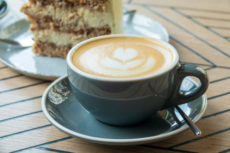Cup of cappuccino and sweet cake. Delicious morning breakfast. Selective focus on cup.の写真素材
