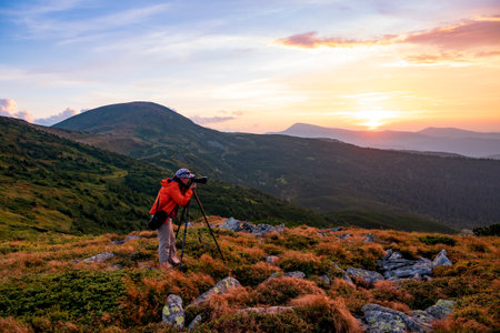 Photographer with the tripod takes photos high in the mountainsの写真素材