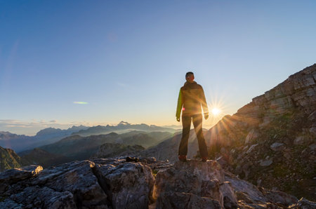Woman standing on the mountain top enjoy sunrise. Symbol of freedom, success, lifetime achievement and active lifestyle.の写真素材