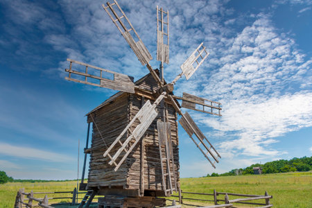 Old wooden windmill on the green meadow with scenic blue sky on the background.の写真素材