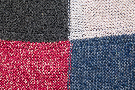Traditional knitting background. Woolen knitted cloth of white, black, blue and red color